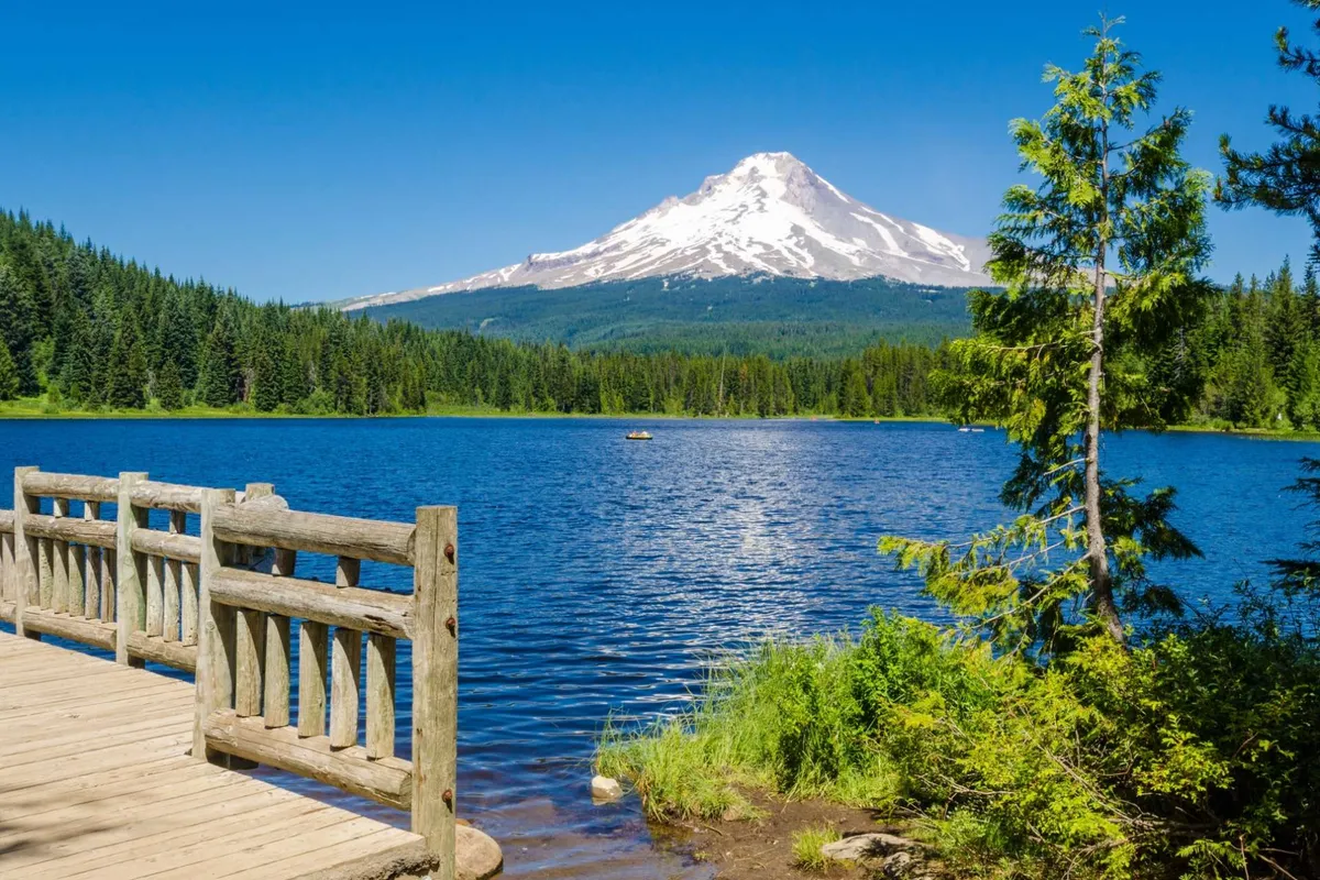 A scenic view featuring a mountain, lake, dock, and trees. Activities like boating, fishing, hiking, and picnicking are suggested by the scene. The mood is serene, with possibilities for wildlife spotting, sunset watching, and enjoying the natural surroundings.