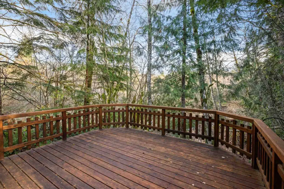 A spacious wooden deck surrounded by lush trees, offering an open and serene space for relaxation, reading, or outdoor meals. The design invites visitors to connect with nature just outside the cabin doors.